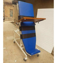 Blue adjustable chair with a wooden table on wheels in an outdoor setting.