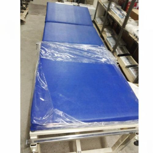 Blue examination table with plastic wrap in a warehouse setting
