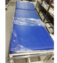 Blue examination table with plastic wrap in a warehouse setting